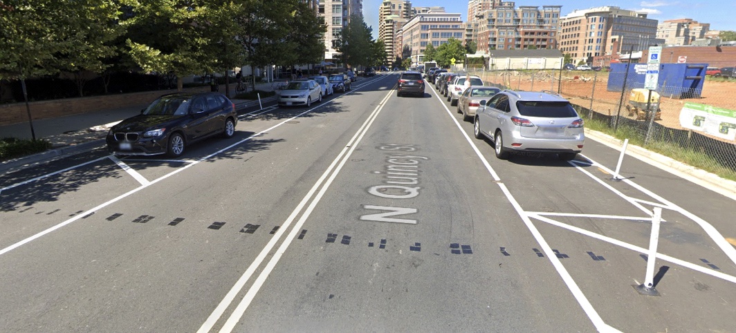 A street where the bike lane is directly adjacent to the curb, followed by a painted buffer space with plastic bollards, followed by parked cars, followed by the travel lane for vehicles.  This configuration is mirrored on the other side of the street.